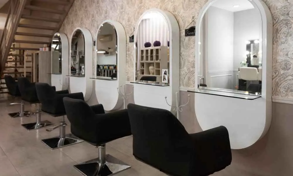 Photo of a beauty salon with a row of empty chairs in front of mirrors.